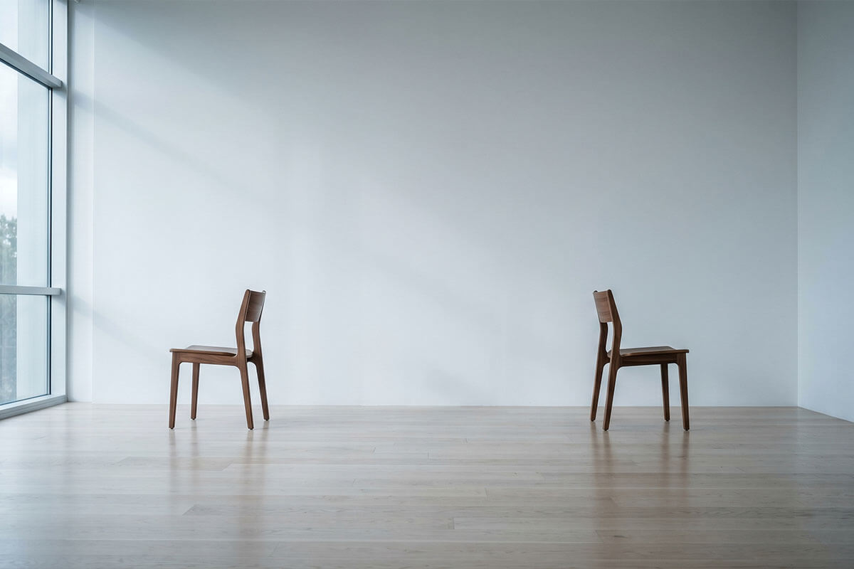 Two chairs facing away from each other representing conflict and disagreement between spouses during a home sale